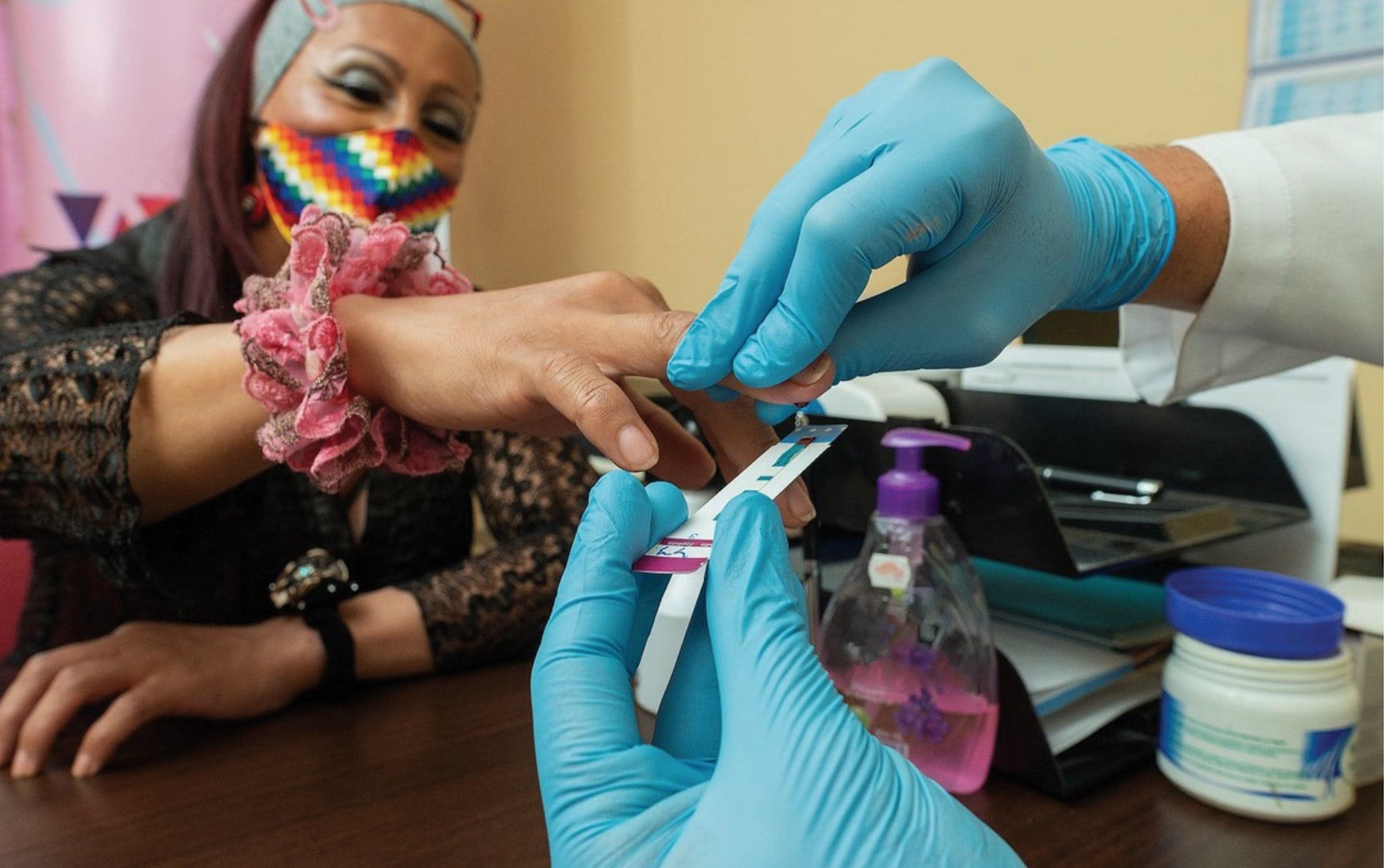 Healthcare professional performing a test on a patient's finger in a medical office.