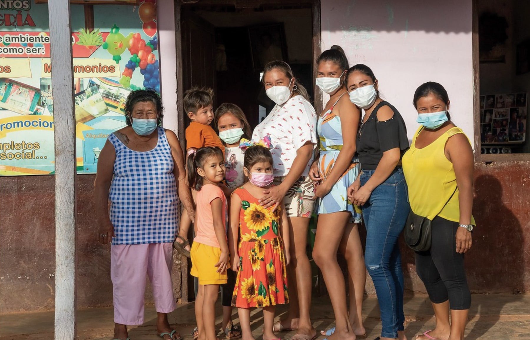 A group of people wearing masks standing in front of a building