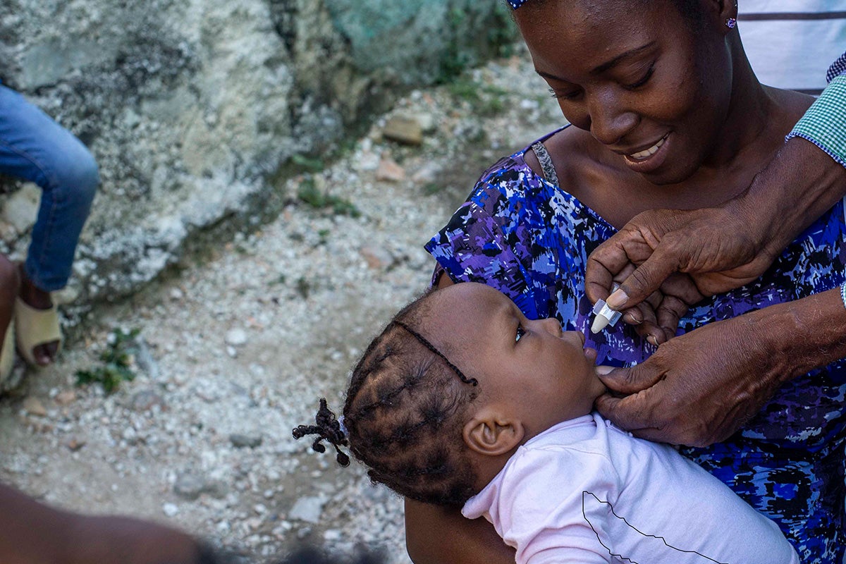 Une mère tient son bébé pendant qu'elle reçoit un vaccin oral