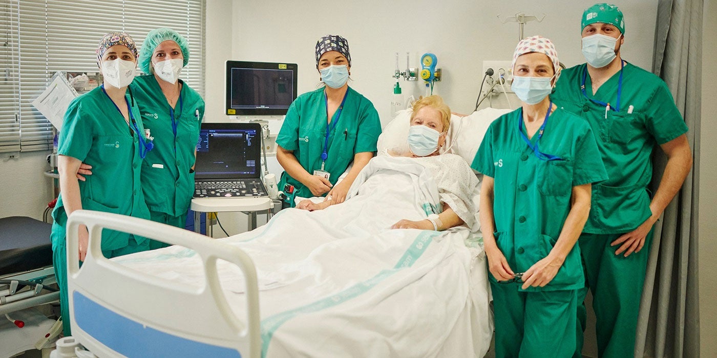 Patient in hospital bed surrounded by health workers