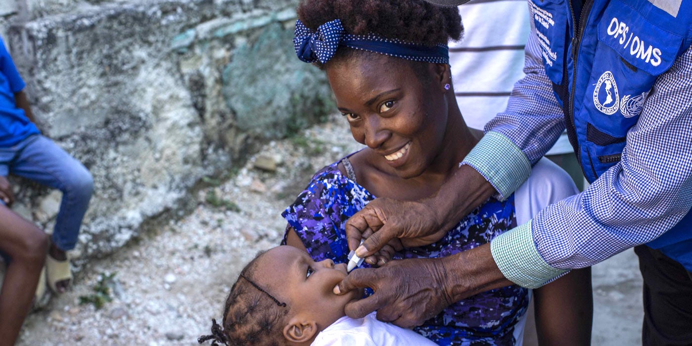 Woman holds a young child who is being vaccinated