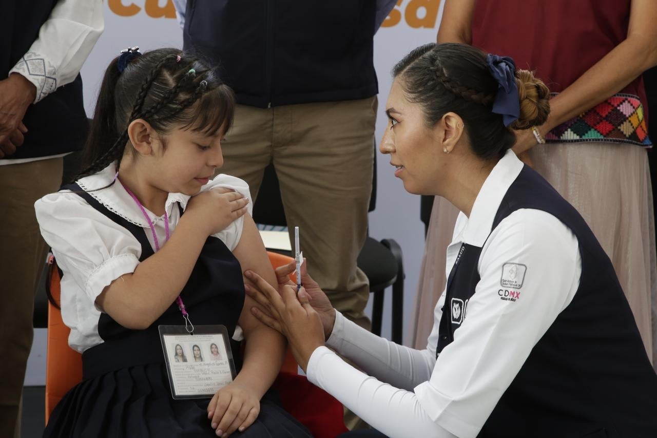 Enfermera vacunando a niña de primaria contra el VPH