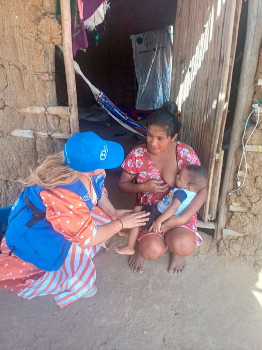 Personal de OPS visita vivienda y conversa con madre que alimenta a su bebé.