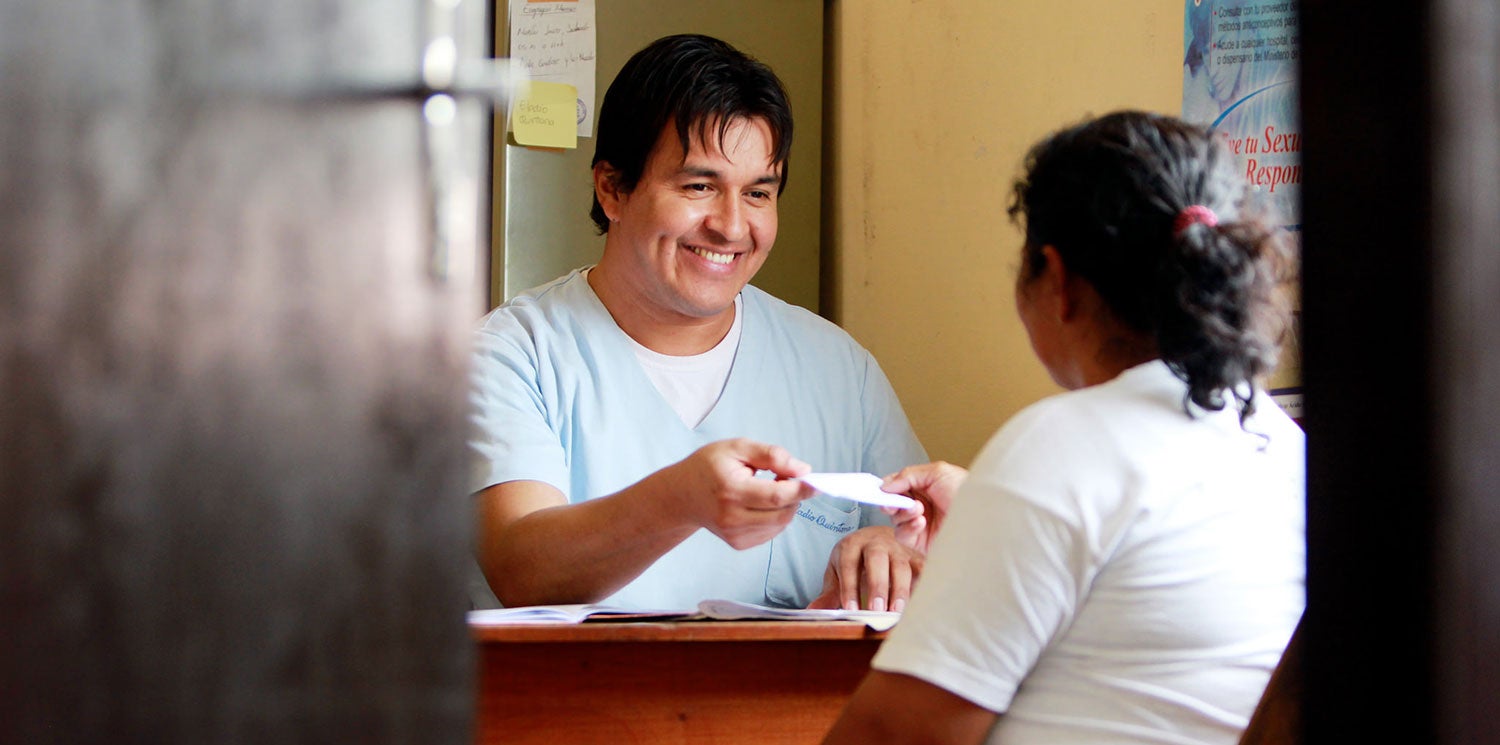 Pharmacist dispenses medication to patient and small window