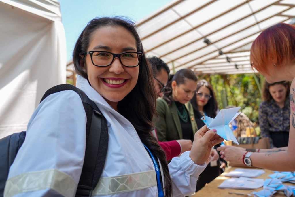 Asistentes al evento de presentación de la Estrategia de Cooepración disfrutan con la elaboración de una paloma de papel 