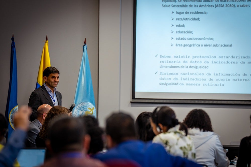 Antonio Sanhueza, asesor de EIH, realizando una exposición. Se ven, difusas, las cabezas de los participantes y parte de la pantalla donde se está proyectando.