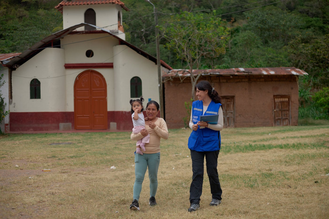 PAHO worker walks with mother and child in town