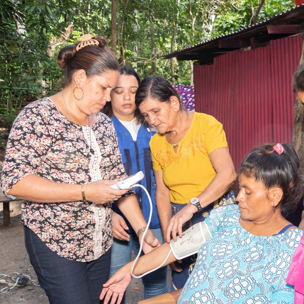 Health worker takes blood pressure of woman in rural area