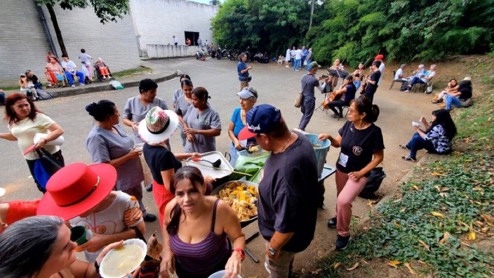 Escena donde se puede ver un grupo de personas sirviendo comida a participantes del encuentro