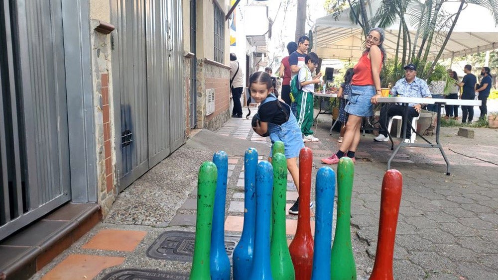 Niña jugando a los bolos en la calle