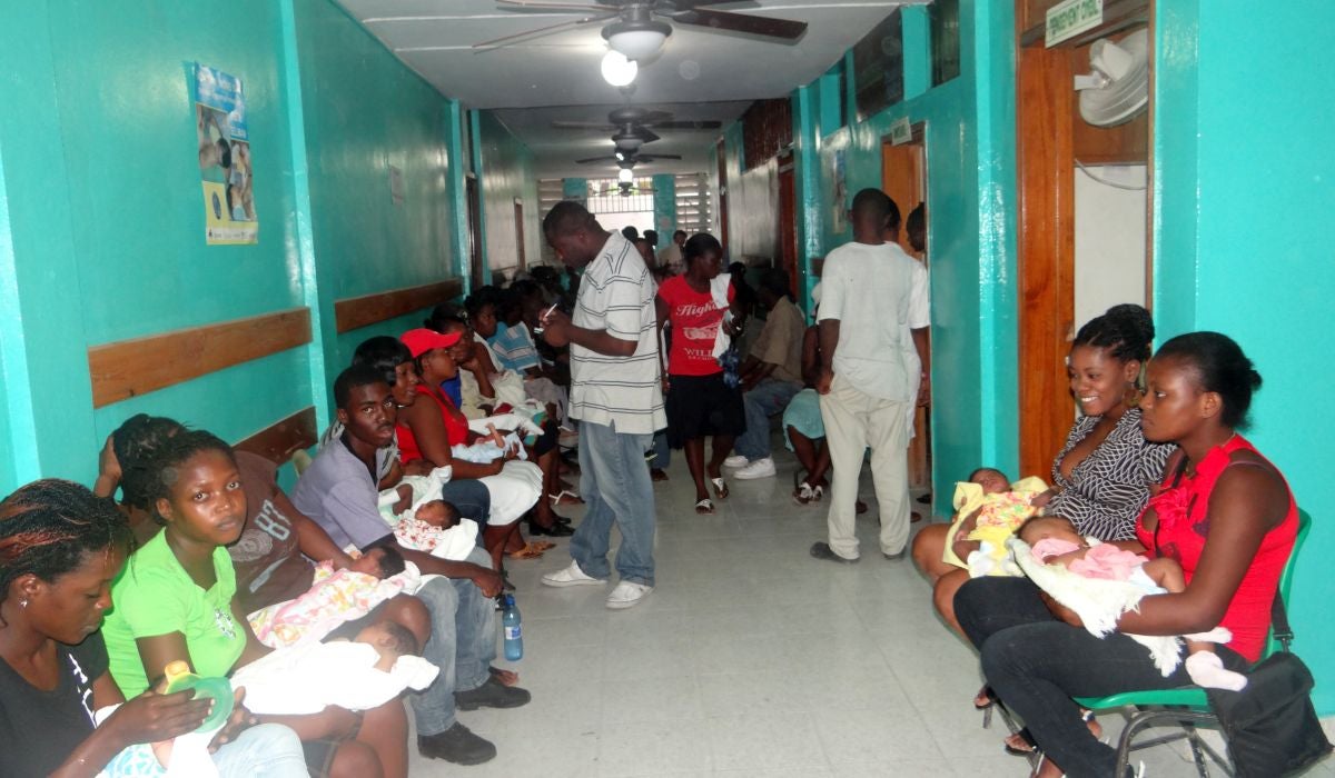 parents and infants wait in a hallway of a haiti hospital