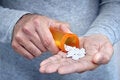 Man pours pills from a jar on his open palm.