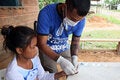 Health worker press finger of young girl against glass to collet blood drop for testing