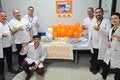 Personal de un centro de salud con distintivos naranja y un stand informativo