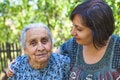 Daughter hugs elderly mother in garden