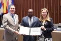 Jean-Patrick Alfred holds the PAHO Award for Management and Leadership. He is standing next to the PAHO Director and the Directing Council president.