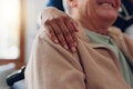 Older man in wheelchair is embraced by caregiver