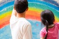 A boy and a girl looking at at painting of a rainbow