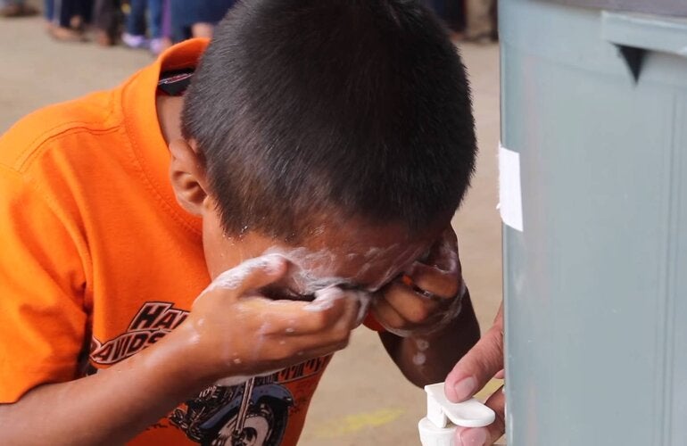 School kid washing his eyes