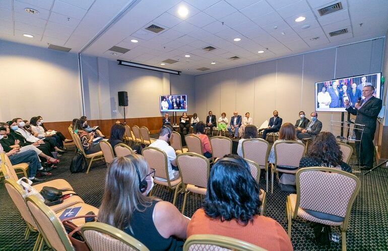 Imagem mostra pessoas em uma sala participando da Reunião Regional de Monitoramento e Reverificação da Eliminação do Sarampo no Brasil