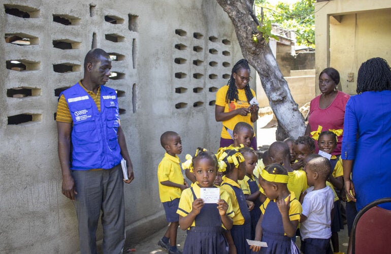 Haiti - Children during vaccination campaign in their community. Girl holding a vaccination card