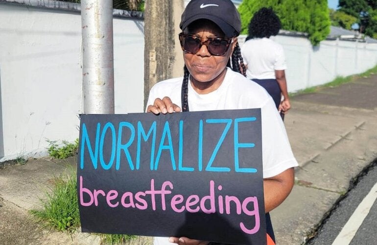 Lady holds sign - Normalize Breastfeeding