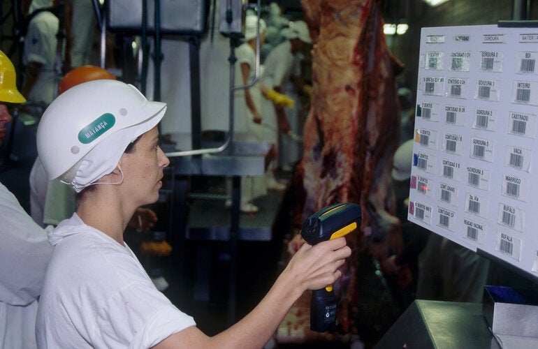 Empleada con casco escaneando códigos de barras en una planta de procesamiento de carne