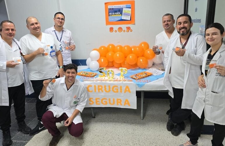 Personal de un centro de salud con distintivos naranja y un stand informativo