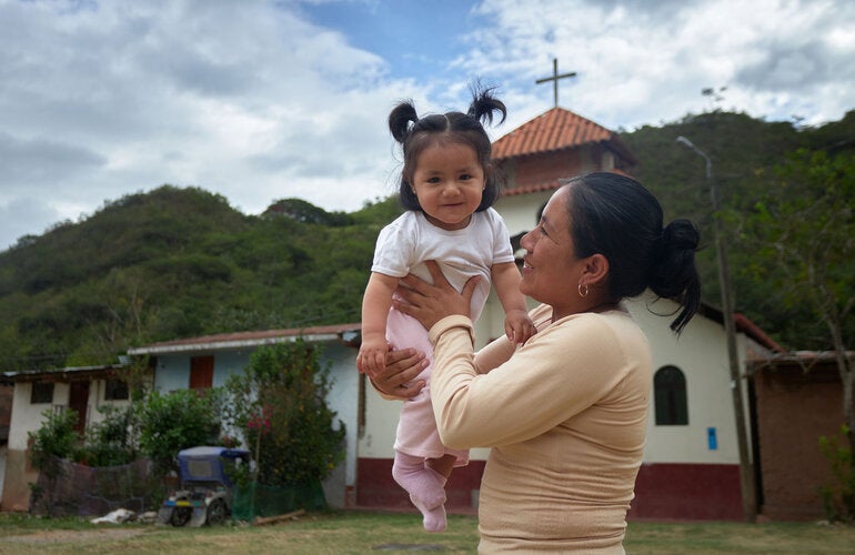 Madre carga a su hija bebé y la eleva