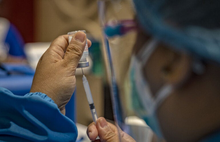 Trabajadora de salud sostiene una jeringa y un vial