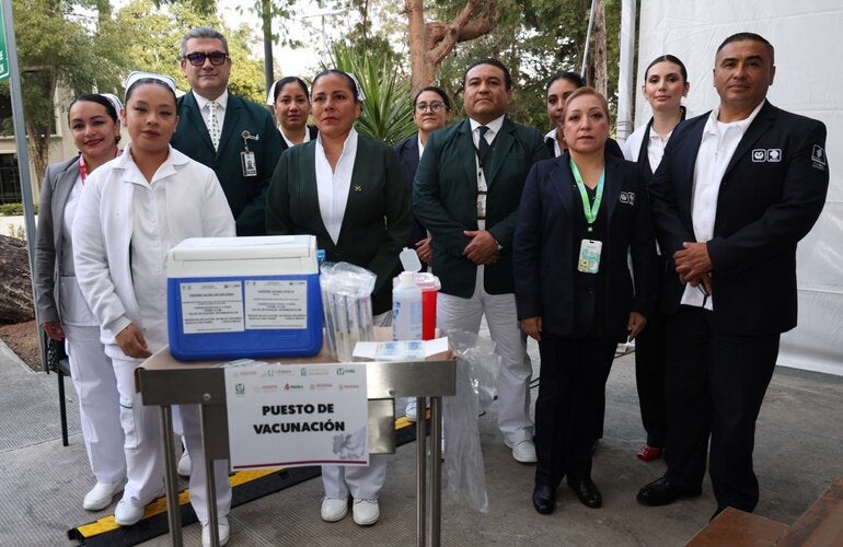 Personal de salud, operativo y directivo alrededor de un puesto de vacunación