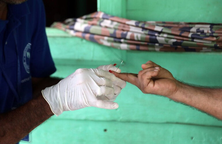 Health worker takes sample from patient to test for the presence of malaria