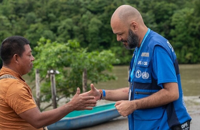 handshake between two men (PAHO personnel and a community leader). Setting: river front