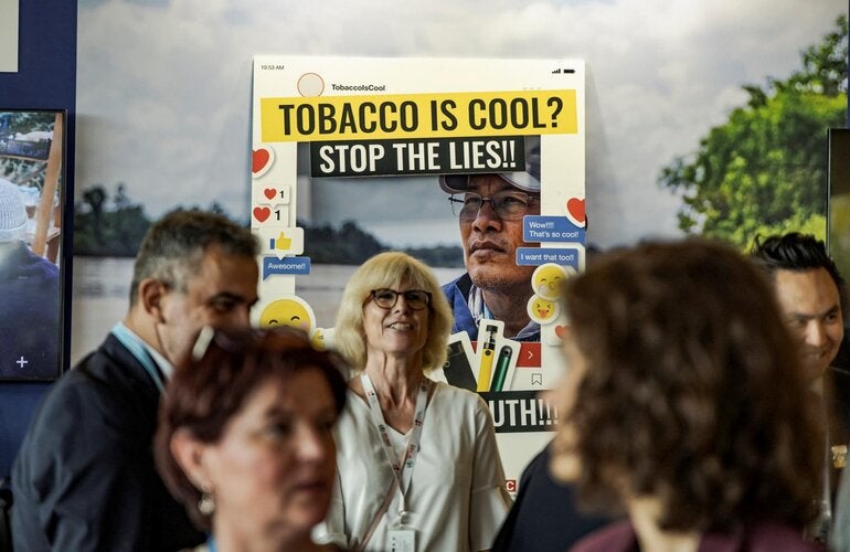 Image of a campaign booth warning about the lies of tobacco products, with some people around it