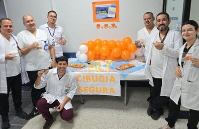 Personal de un centro de salud con distintivos naranja y un stand informativo