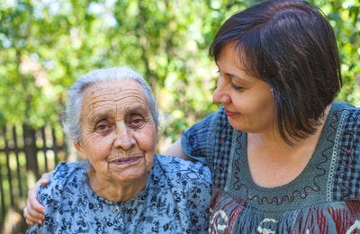 Daughter hugs elderly mother in garden