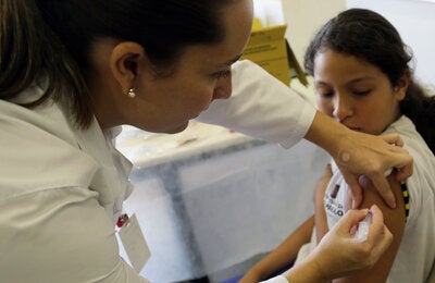 Healthcare professional vaccinates a teen girl in the arm against HPV