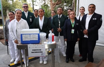 Personal de salud, operativo y directivo alrededor de un puesto de vacunación