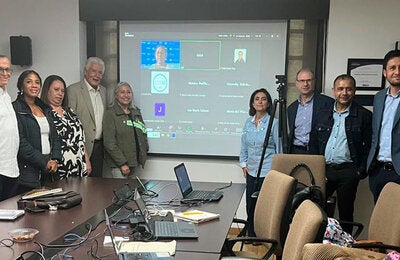 Grupo de personas de OPS y la academia reunios presencialmentey virtualmente