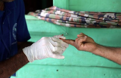 Health worker takes sample from patient to test for the presence of malaria