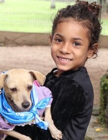 Niña con perro en brazos en campaña de vacunación contra la rabia en PANAFTOSA