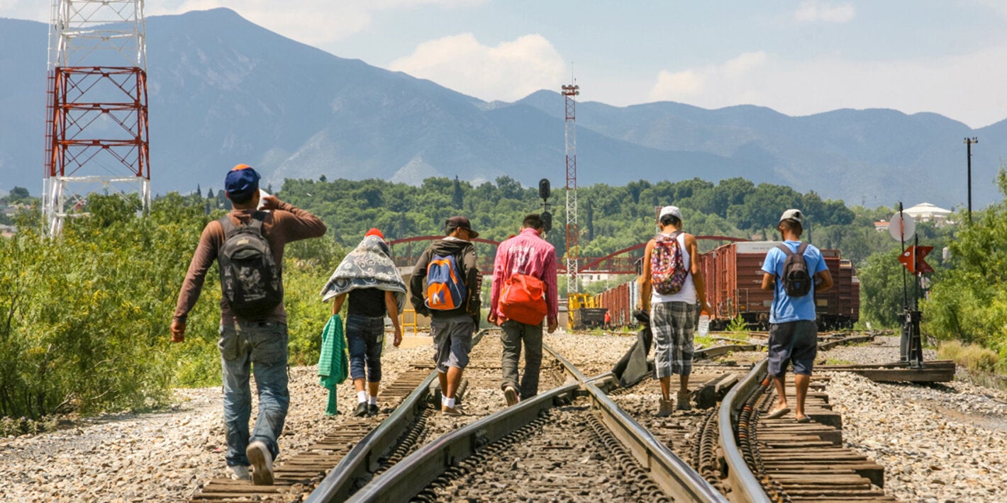 migrants walking on railroad tracks