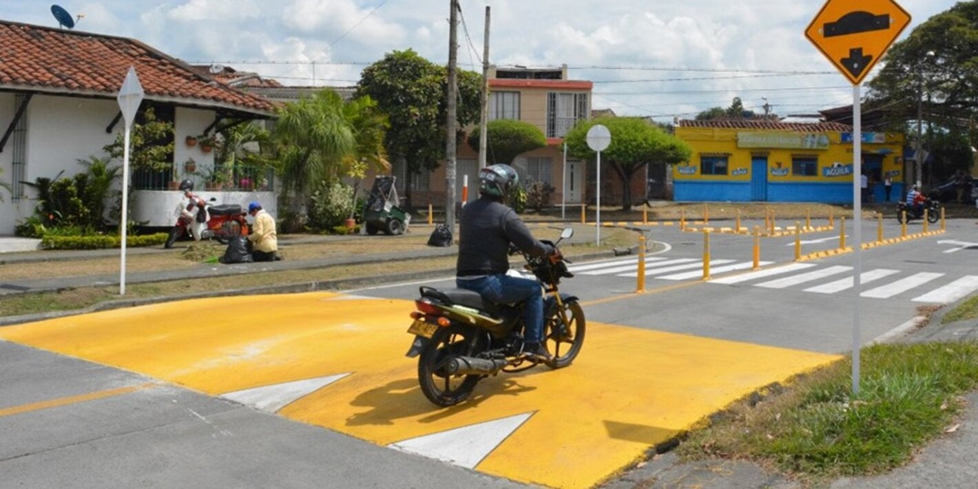 Motociclista en la calle pasando un reductor de velocidad