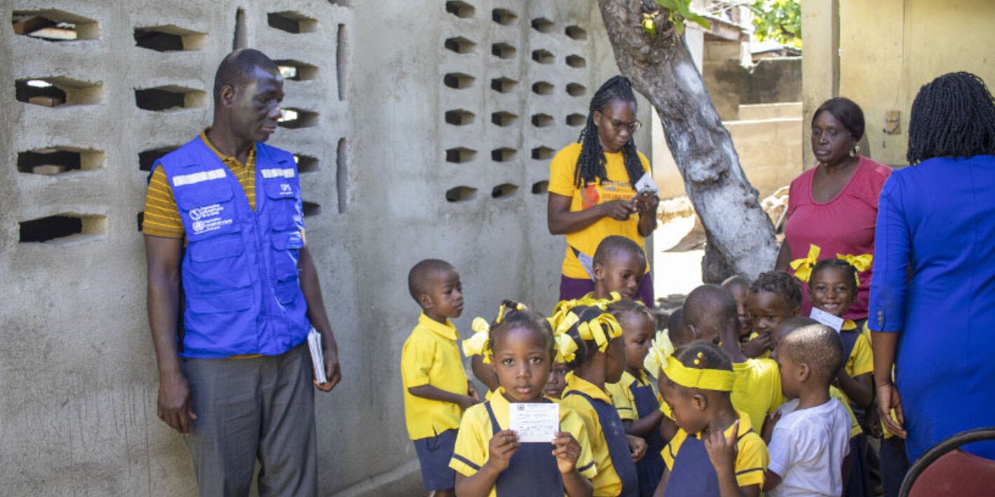 Haiti - Children during vaccination campaign in their community. Girl holding a vaccination card