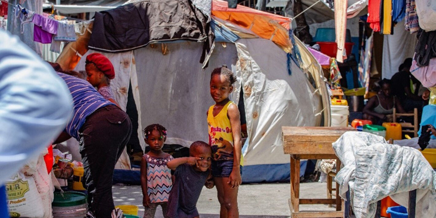 Niños sonríen a la cámara en un campamento en Haití