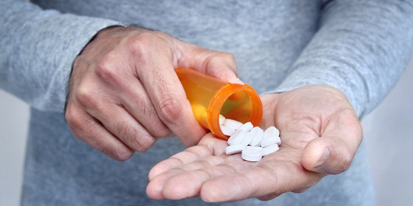 Man pours pills from a jar on his open palm.