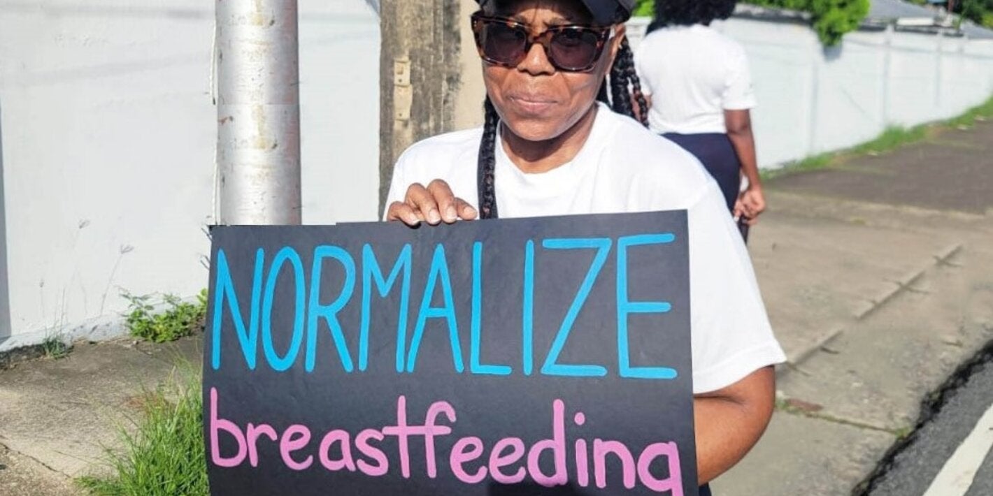 Lady holds sign - Normalize Breastfeeding