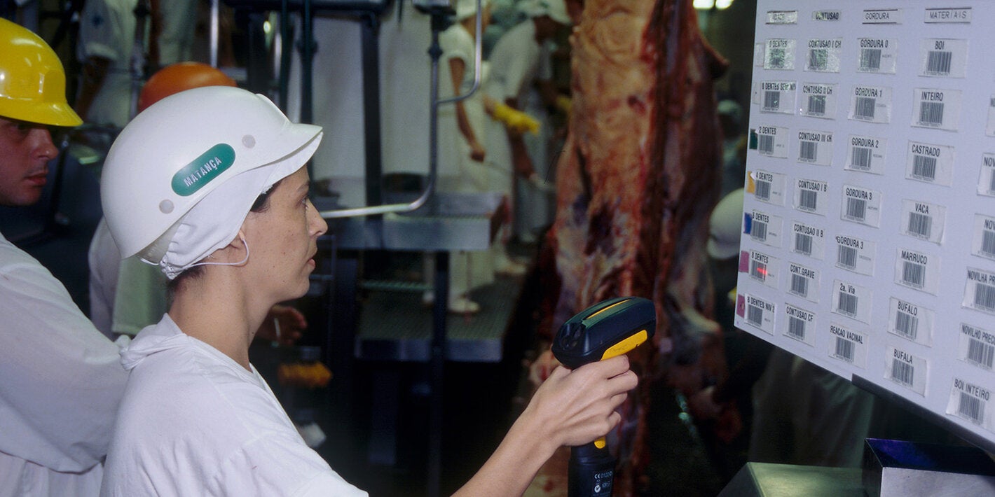 Empleada con casco escaneando códigos de barras en una planta de procesamiento de carne