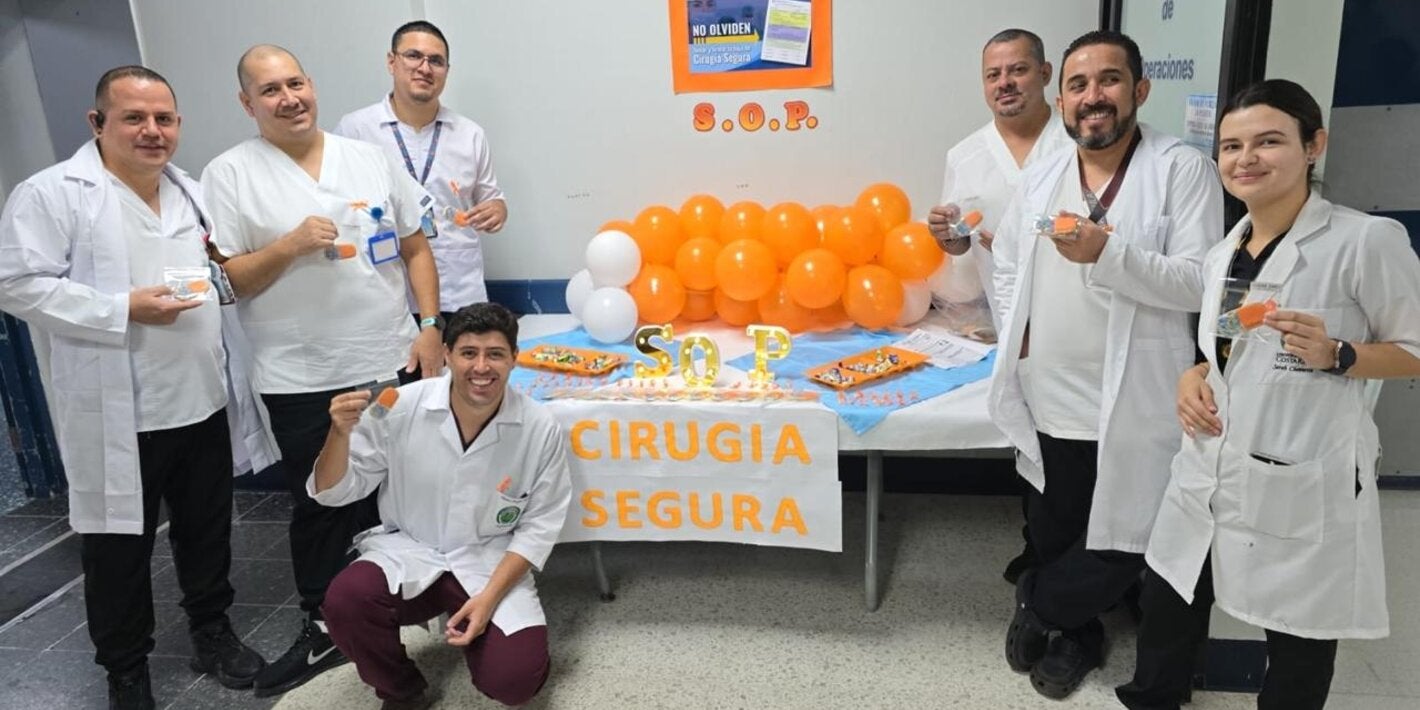 Personal de un centro de salud con distintivos naranja y un stand informativo