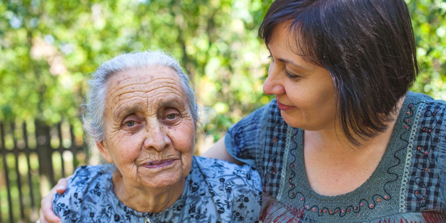 Hija abraza a madre mayor en el jardín